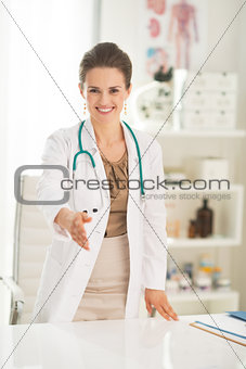 Smiling medical doctor woman stretching hand for handshake