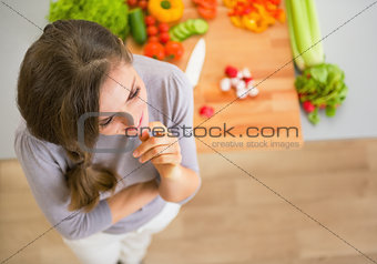 Portrait of thoughtful young housewife in kitchen