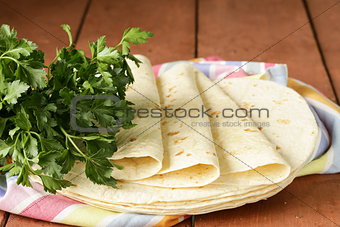 stack of homemade whole wheat flour tortillas on a wooden table