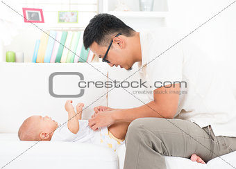 Father changing diaper and clothes for baby.
