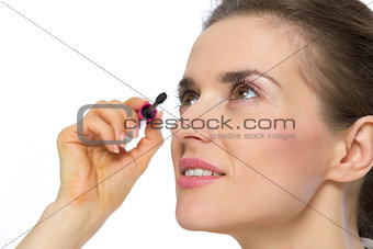 Portrait of young woman applying mascara