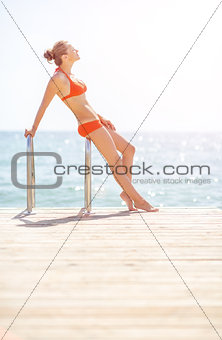 Full length portrait of young woman standing on bridge