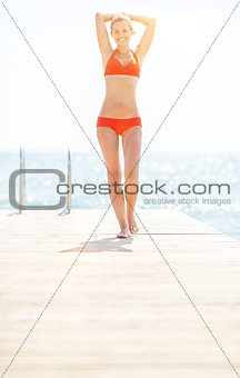 Full length portrait of happy young woman on bridge going straig