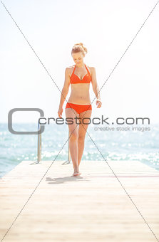 Full length portrait of young woman on bridge going straight