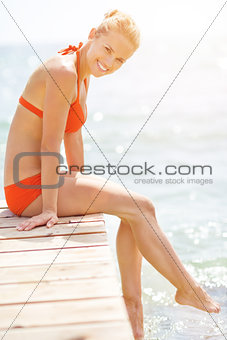 Smiling young woman sitting on bridge