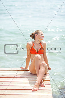 Relaxed young woman sitting on bridge