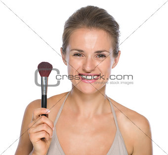 Portrait of smiling young woman showing makeup brush