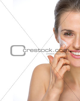 Closeup on happy young woman applying creme