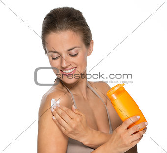 Happy young woman applying sun screen creme