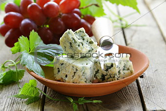 pieces of blue cheese with red grapes on a wooden table