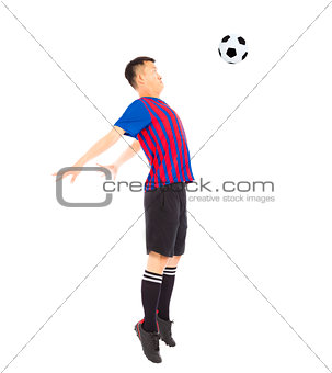 Young soccer player jumping to stop ball by chest