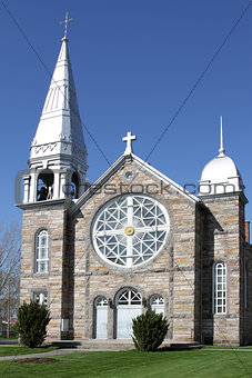 Grey stone church with a large round glass window