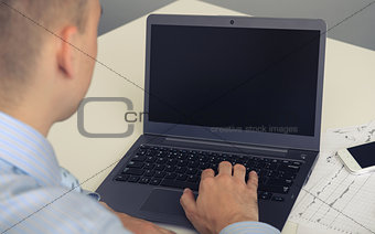 Rear view closeup of a young man working of a laptop