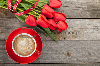 Fresh red tulips with ribbon and coffee cup with heart shape