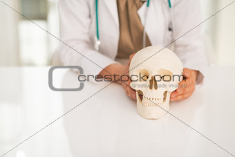 Closeup on medical doctor woman holding human skull