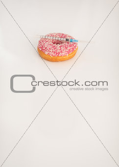 Closeup on donut and diabetes syringe on table