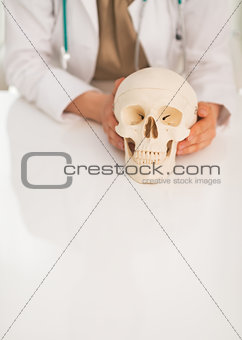 Closeup on medical doctor woman holding human skull