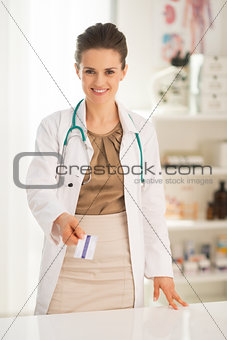 Happy medical doctor woman giving business card