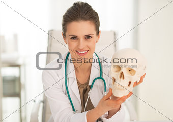 Portrait of happy medical doctor woman showing human skull