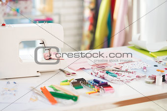 Closeup on table of seamstress with scissors threads and fabric