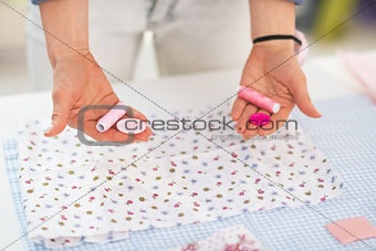 Closeup on seamstress choosing between buttons and threads