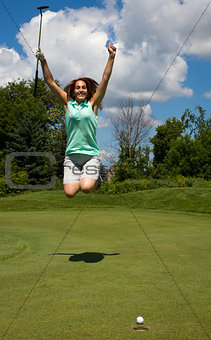 Woman jumping for joy as the golf ball heads into the cup
