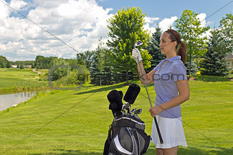 Golfing woman selects her club on the fairway