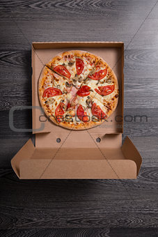 Italian pizza with ham and tomatoes in box 