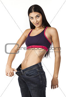 Astonished young woman in old jeans pants after losing weight