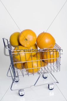A shopping cart full of fresh whole oranges against a white background.