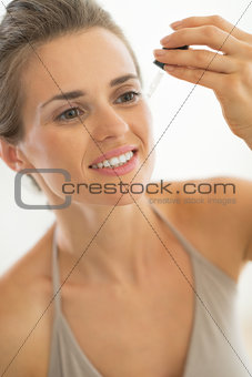 Portrait of young woman applying cosmetic elixir