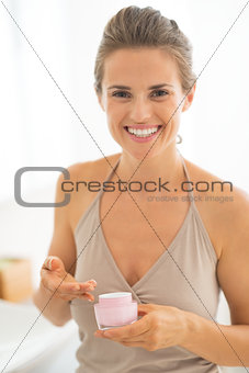 Portrait of happy young woman with cream in bathroom