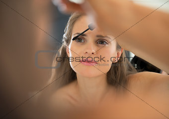 Portrait of young woman applying mascara