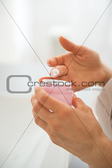 Closeup on young woman applying cream