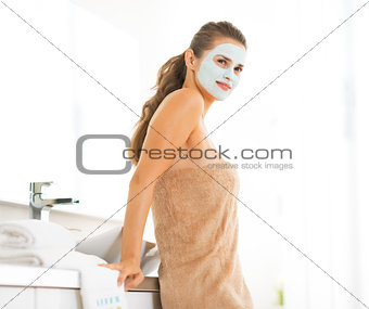 Portrait of happy young woman wearing facial cosmetic mask