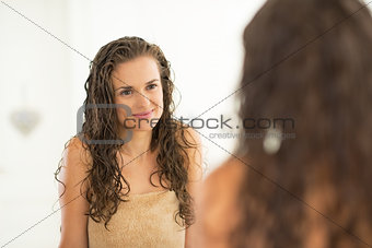 Portrait of young woman with wet hair looking in mirror