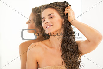 Portrait of relaxed young woman with long wet hair near mirror