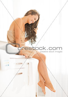Young woman with long wet hair sitting in bathroom