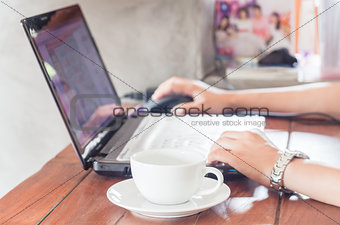 Woman using laptop with a cup of coffee