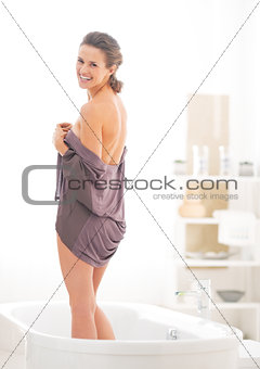 Young woman standing in bathtub