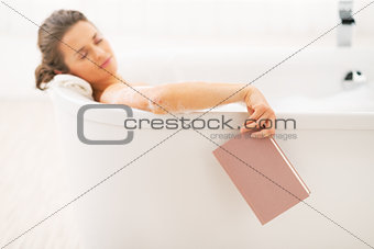 Young woman fall asleep while reading book in bathtub