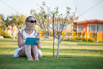 Beautiful woman sitting barefoot on a lawn