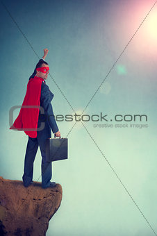 superhero businessman standing on the edge of a cliff