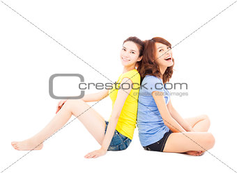 two smiling  young woman sitting and back to back