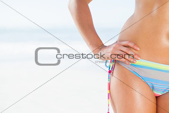 Mid section of fit woman in bikini on the beach