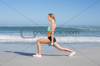 Fit woman doing weighted lunges on the beach