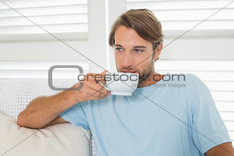 Handsome casual man sitting on couch having coffee