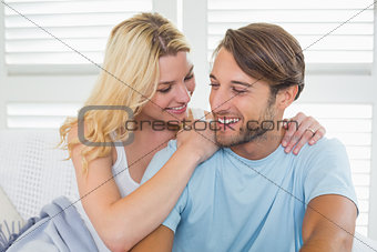 Cute casual couple sitting on couch under blanket