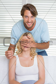 Handsome man covering his girlfriends eyes about to propose