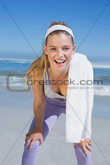Sporty smiling blonde standing on the beach with towel